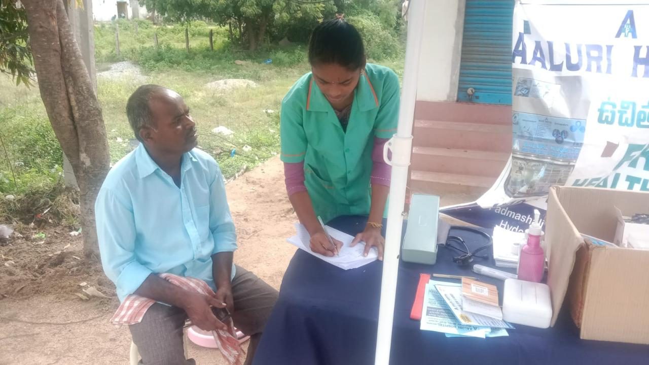 Nurse recording patient details at a community health camp