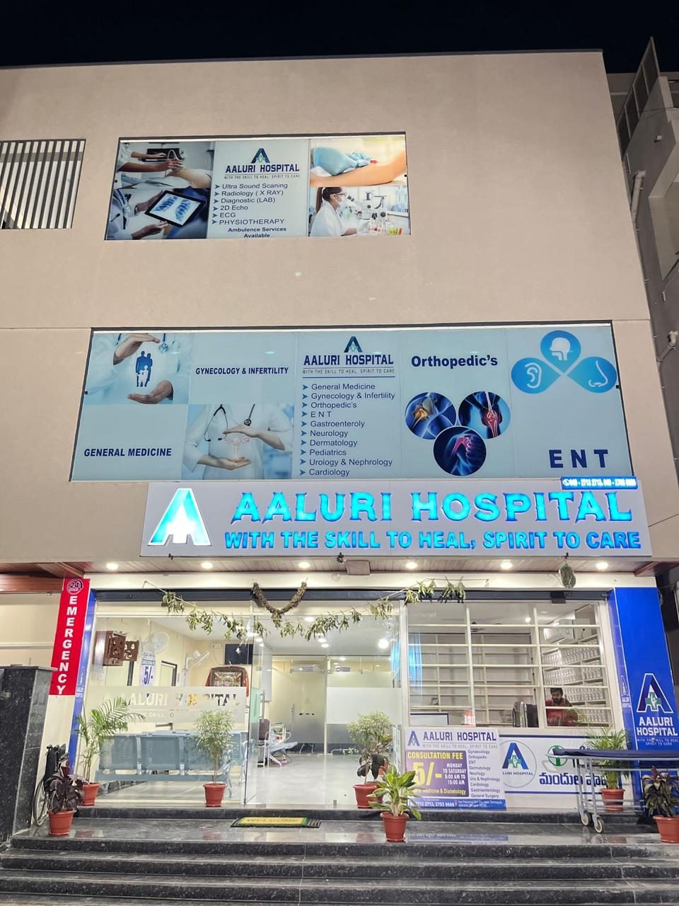 Aaluri Hospital evening view with illuminated signage showing all departments